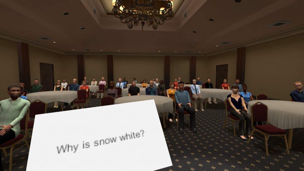 A presentation in a large room with round tables. An impromptu topic on a notecard is visible, "Why is snow white?"