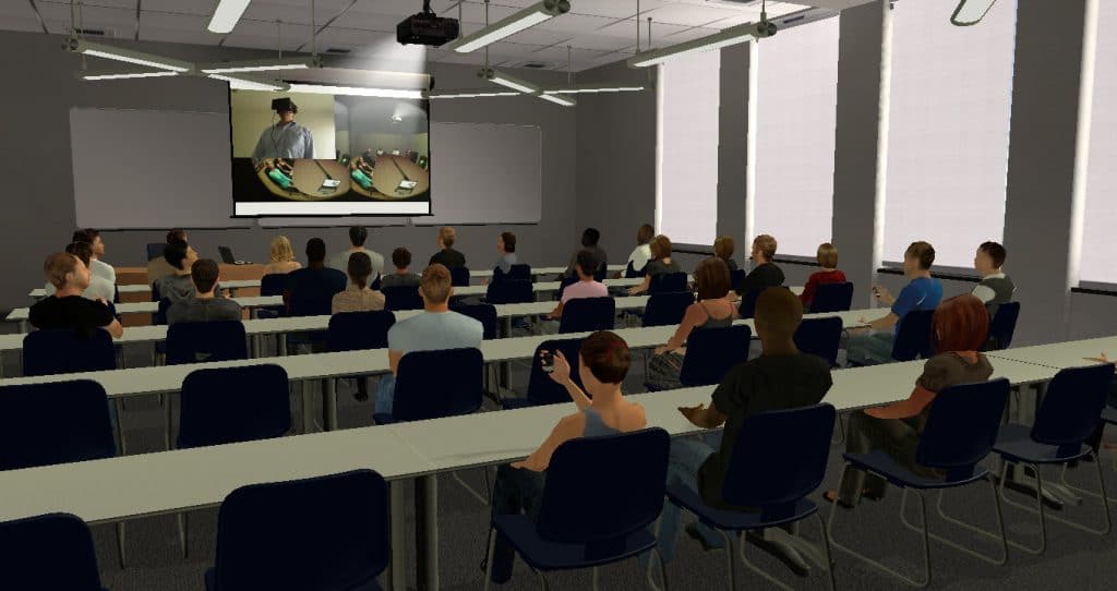 Classroom setup for a slide presentation, seen from the back of the room. The projection is showing an image of someone using an HMD in Virtual Orator taken from the recording mechanism. The audience is mostly attentive, but we see a few at the back using their mobile telephones.