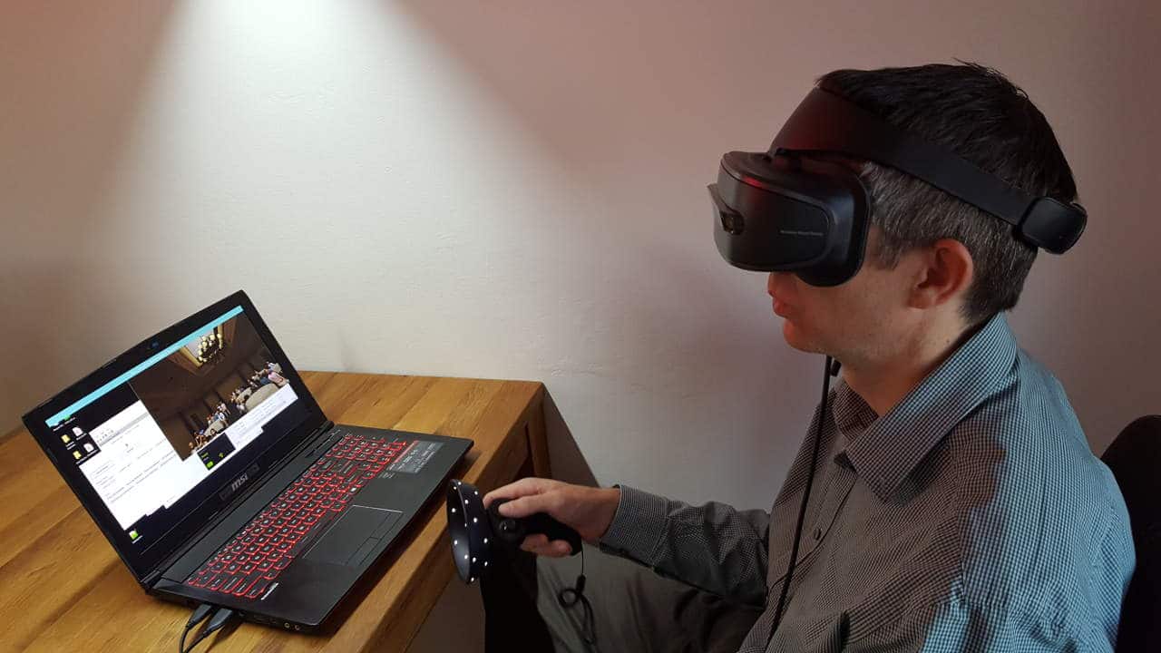 A man in a Windows Mixed Reality headset uses Virtual Orator, running on a laptop.